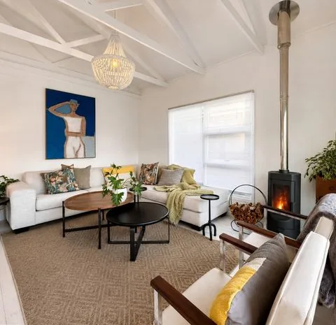 Bright beach house living room with a sectional sofa, wood-burning fireplace and coastal décor