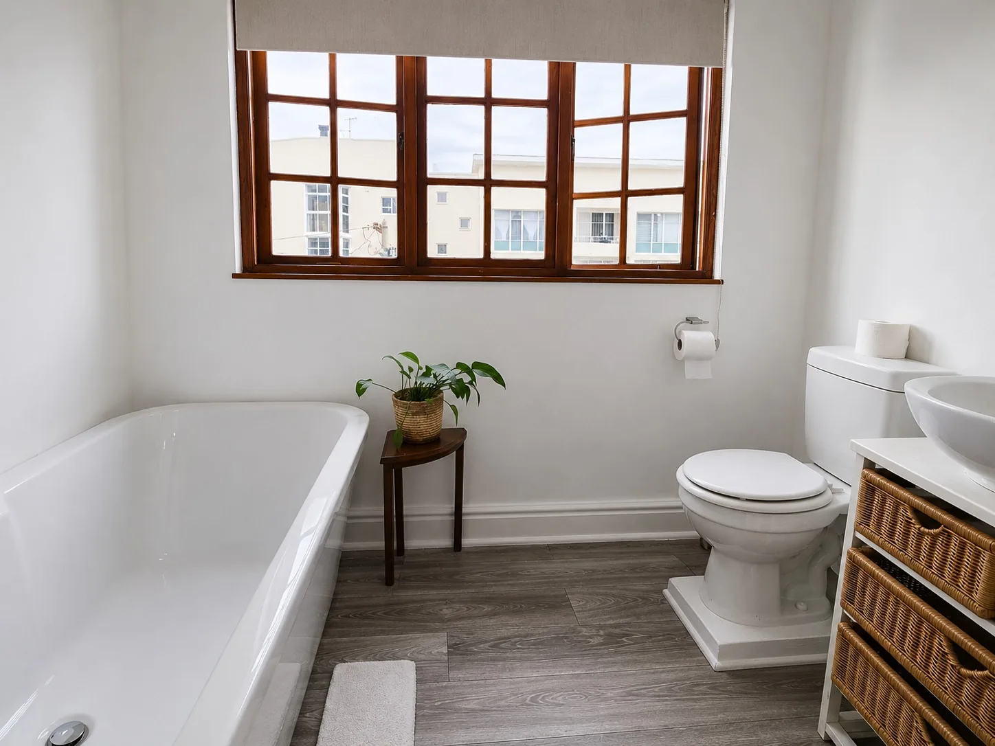 Bright bathroom at Loddeys Family Room with a full-size bathtub, basin, toilet and wooden-framed windows