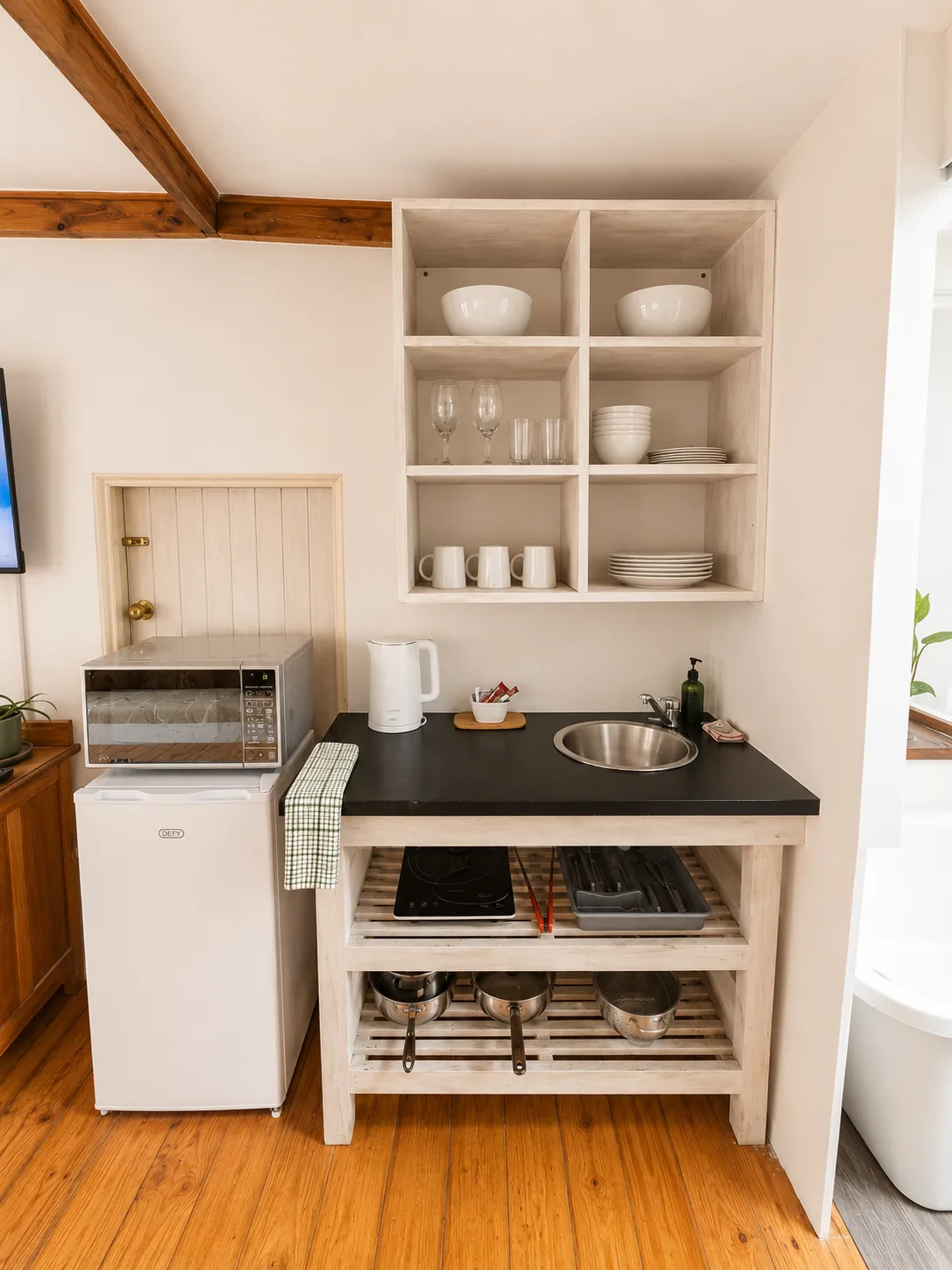 Compact self-catering kitchenette at Loddeys Family Room with refrigerator, microwave, sink, hotplate and open shelving