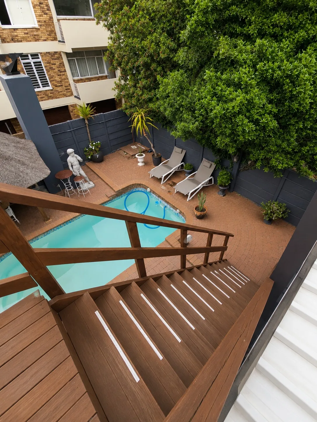 Elevated view from Loddeys Family Room overlooking the swimming pool, sun loungers and leafy courtyard