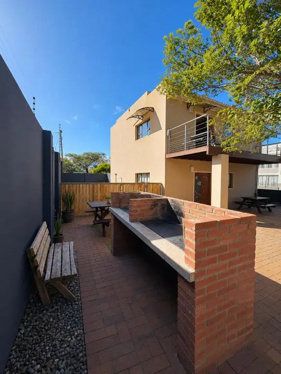 Outdoor brick braai and seating area at Ocean Walk with a view of the house and upper balcony