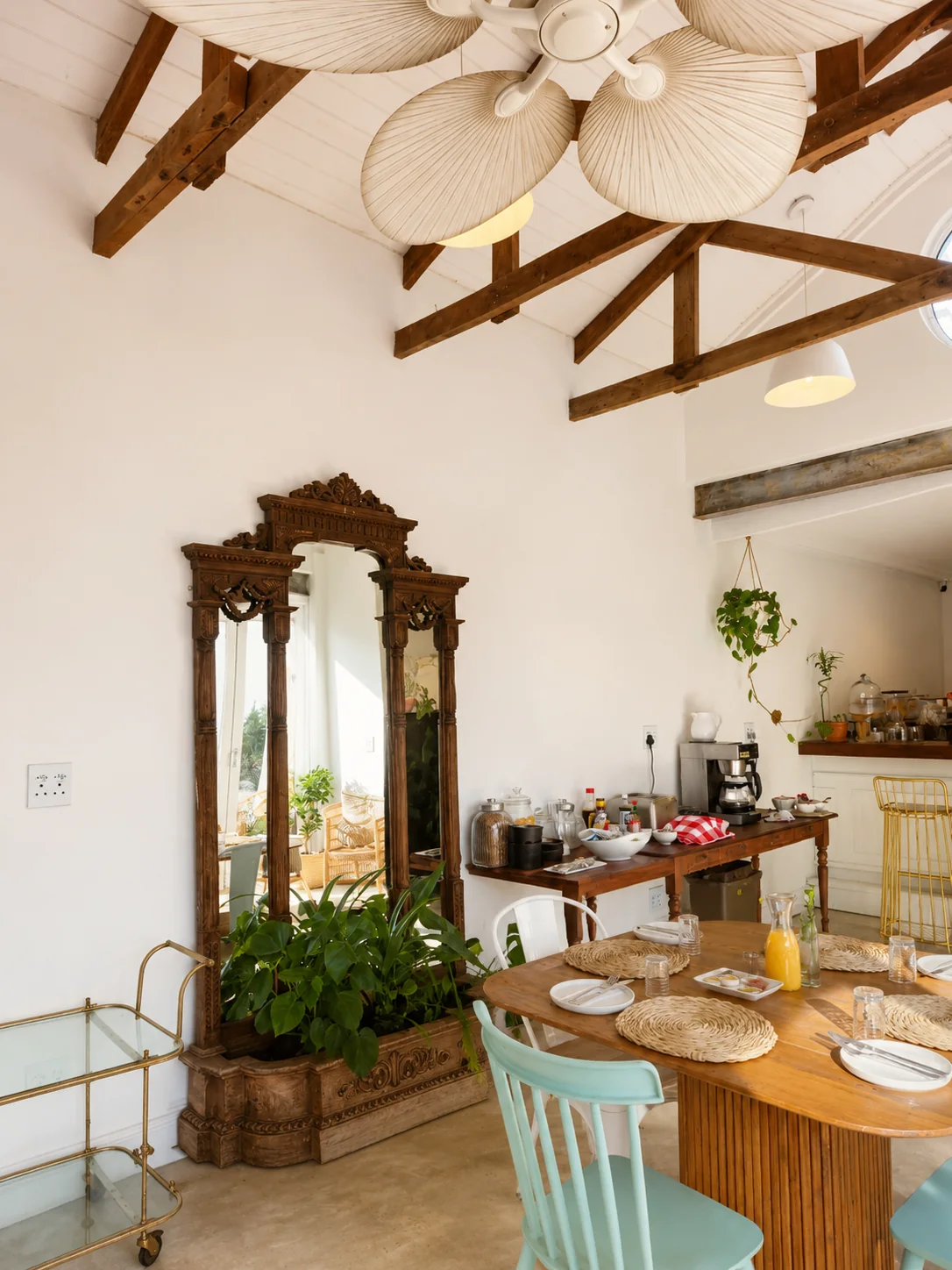 Bright restaurant breakfast dining area with wooden tables, exposed beams, plants and buffet station