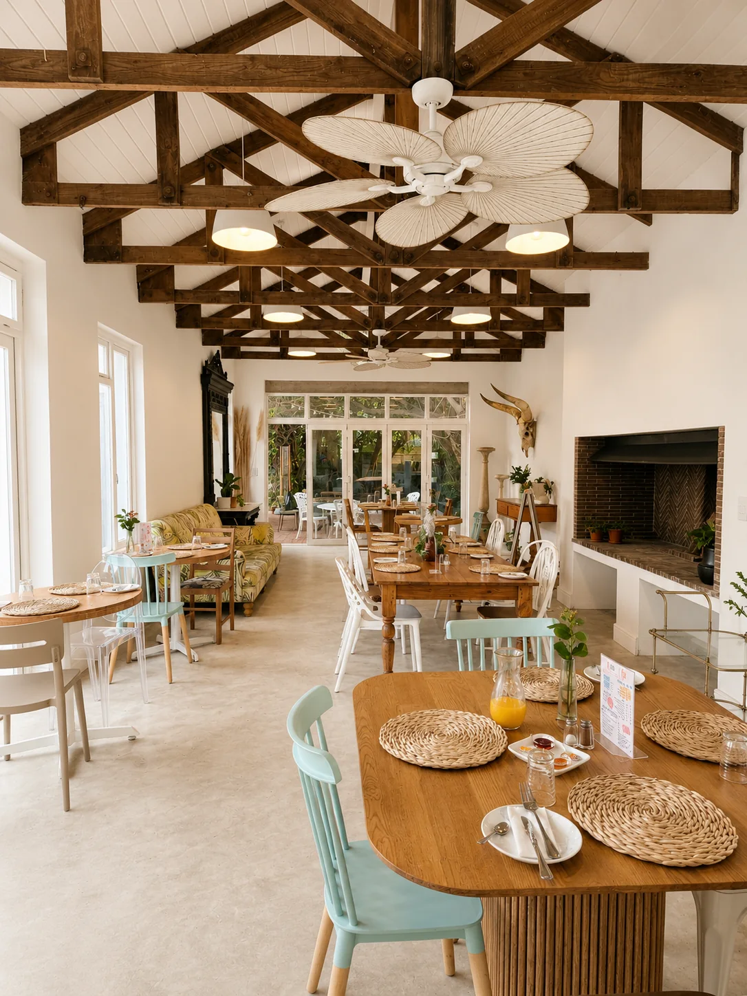 Full view of restaurant dining room with wooden tables, exposed roof beams and courtyard beyond