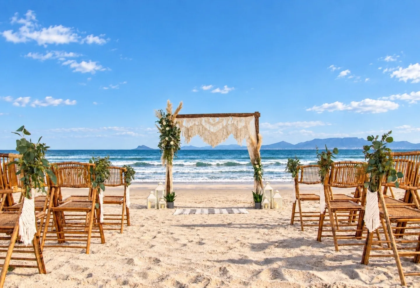 beach-collection-beach-wedding-ceremony-ocean-view Beach wedding ceremony setup with wooden chairs, a macrame arch and ocean and mountain views.